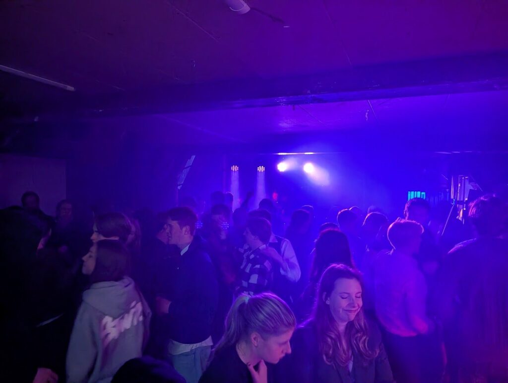 Dansende gasten op een clubfeest met paarse en blauwe verlichting