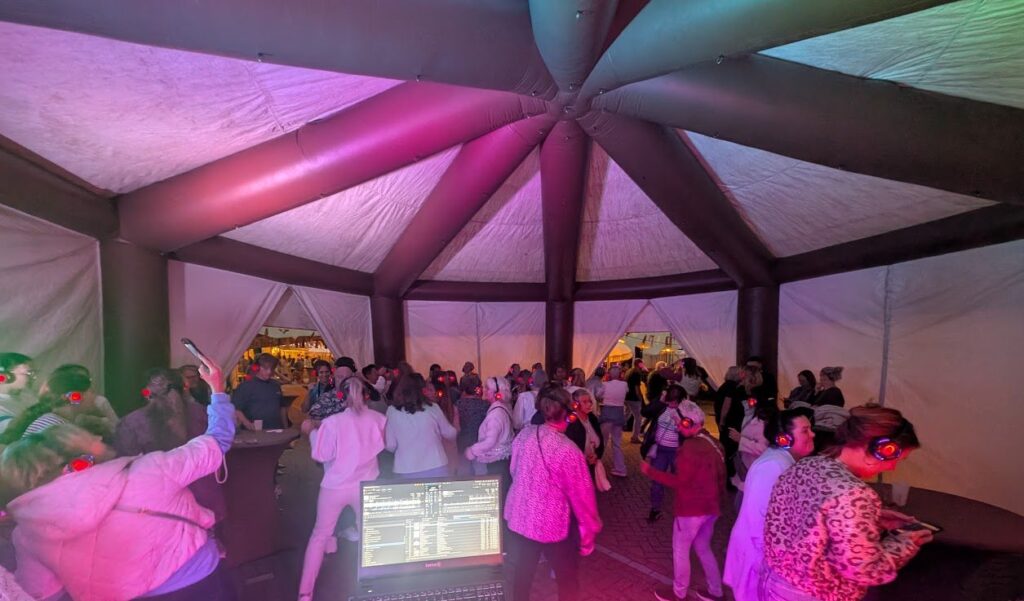 Silent disco met dansende gasten in een sfeervol verlichte feesttent