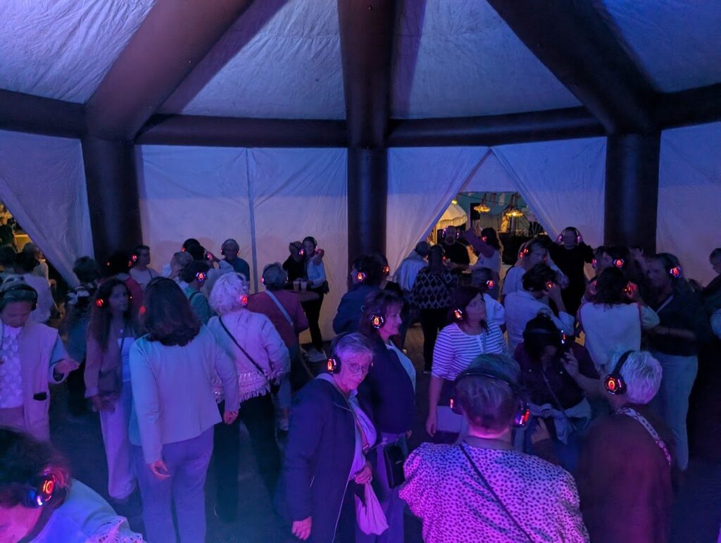 Volle dansvloer tijdens een silent disco in een grote feesttent